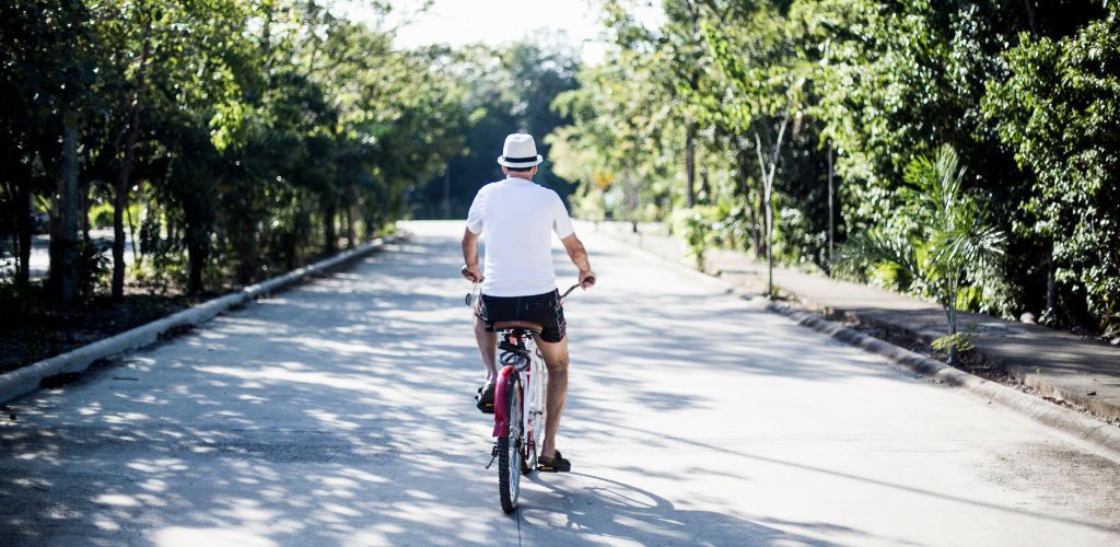 A Man Riding a Bike Through The Lush Streets of Tulum