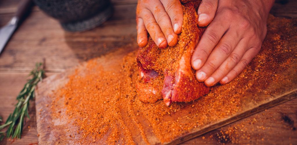 A man rubbing spices on a piece of meat
