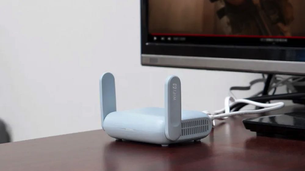 a travel router sitting on a desk with a computer