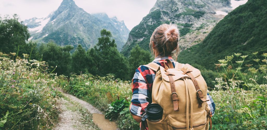 There is a one woman surrounded by forested mountains. 