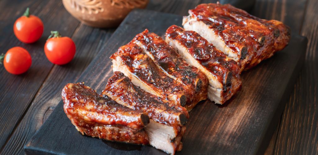 Delicious pork ribs served in a platter with fresh tomatoes on the side