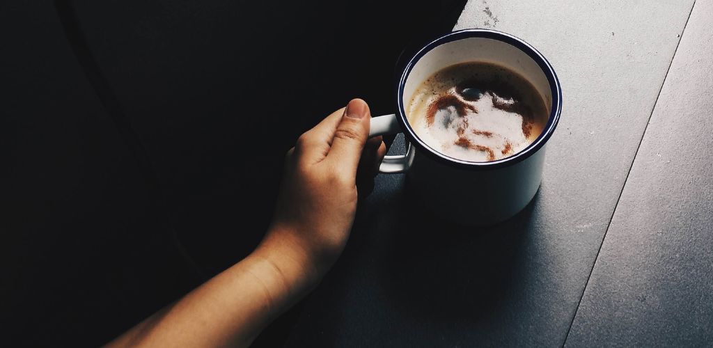 A coffee mug with someone holding it on a dark ambiance