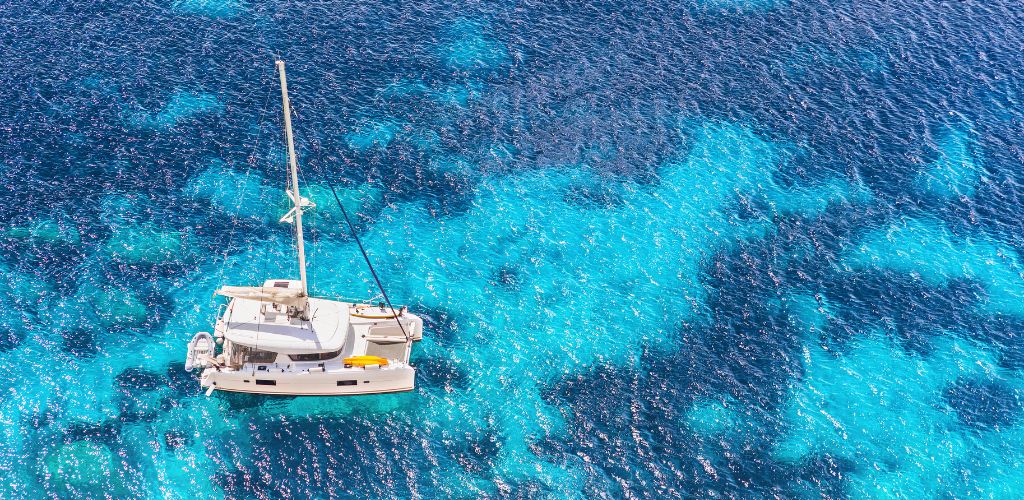 Sailing Tour on a Catamaran in Tulum. Aerial view of the Catamaran sailing over the crystal clear Caribbean Sea