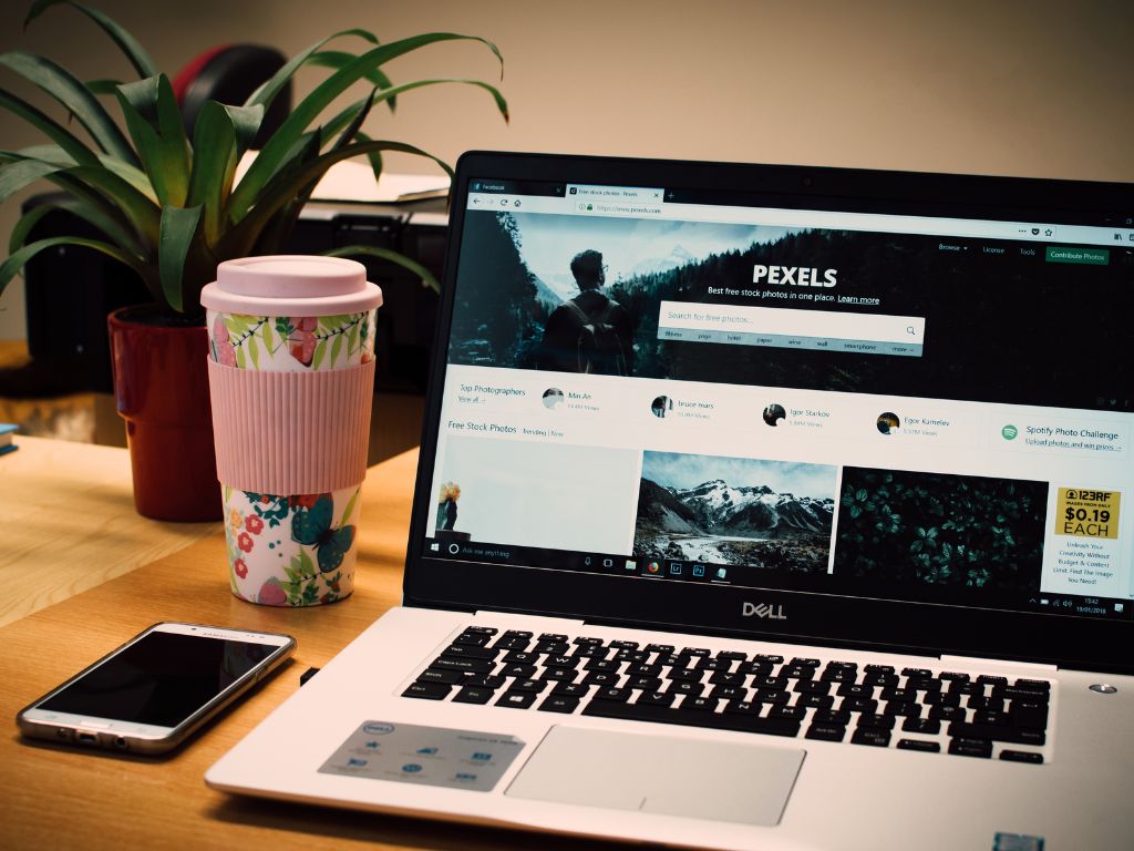 a laptop with a smartphone and a coffee mug cup next to it