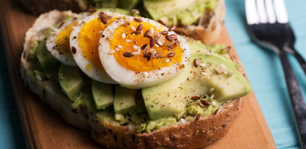 Eggs on Toasts with avocado on a wooden board
