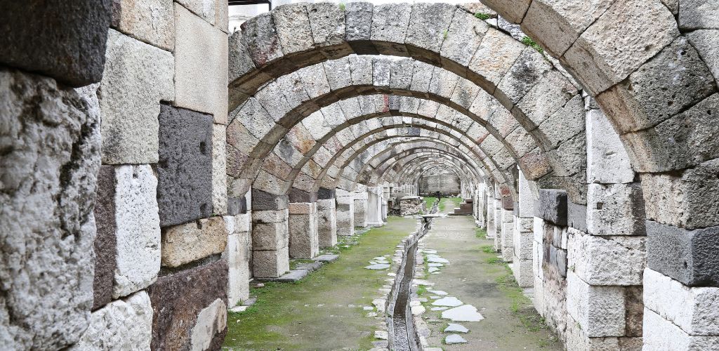 A historical path shaped like an antique stone arch. In the center, there is a little water canal. 