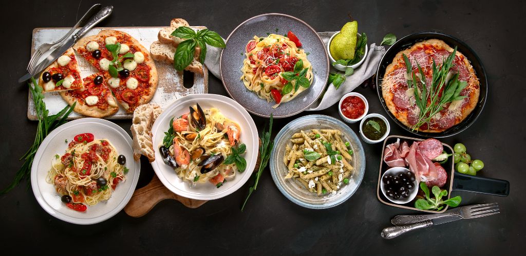 Italian food on a dark background, with a top view of pasta and pizza. 