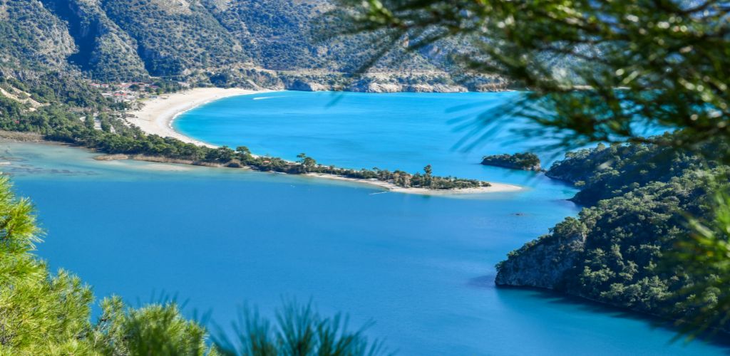 A beautiful beach with blue seawater. and surrounded by green mountains.