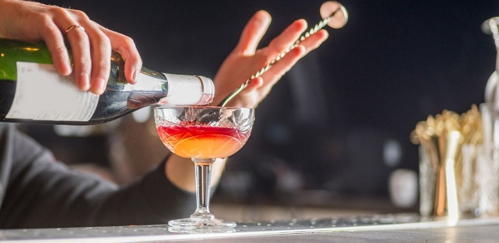 the bartender is preparing a cocktail. The bartender pours a cocktail.