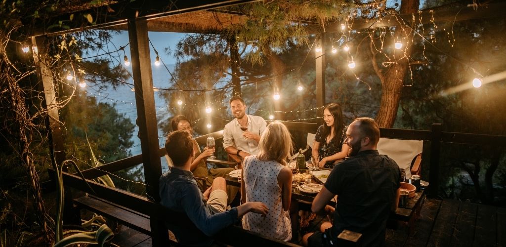 A group of people enjoying a meal in the middle of mangrove and seawater, and surrounded by yellow lights. 