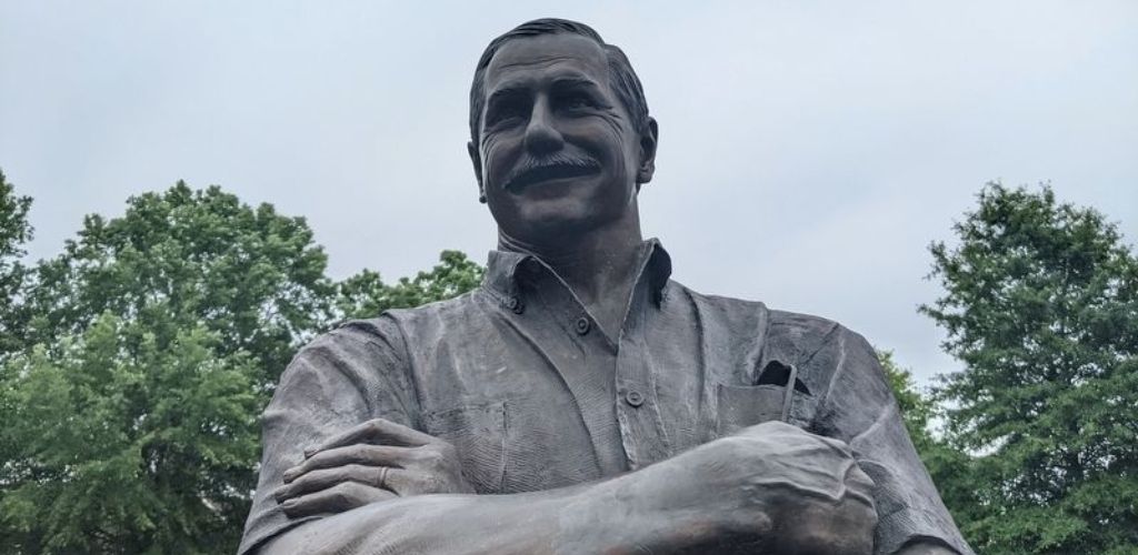 Dale Earnhardt’s smiling statue with green trees in the background. 