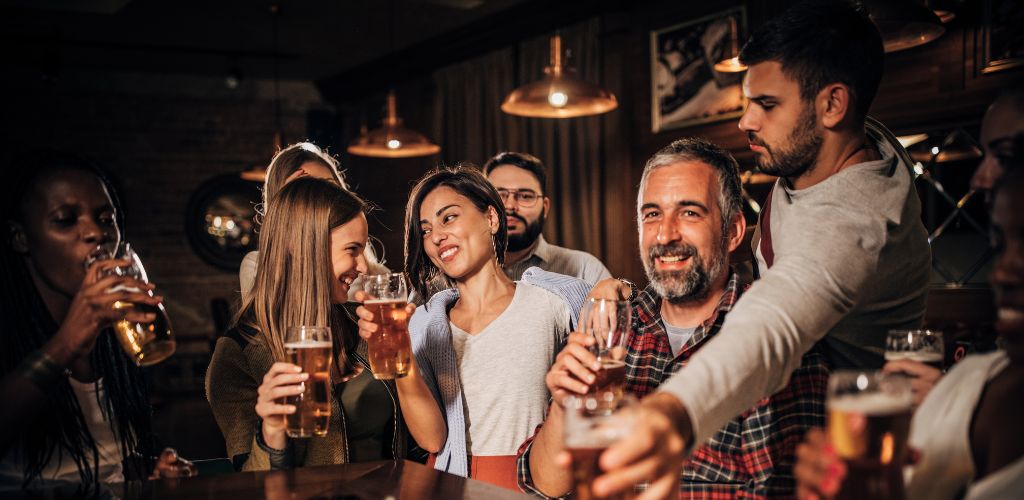 A group of women and men are holding a glass of beer and enjoying themselves.