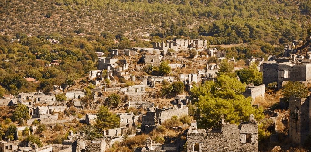 Kayaköy, Fethiye, a lot of building structures and surrounded of mountain and trees. 