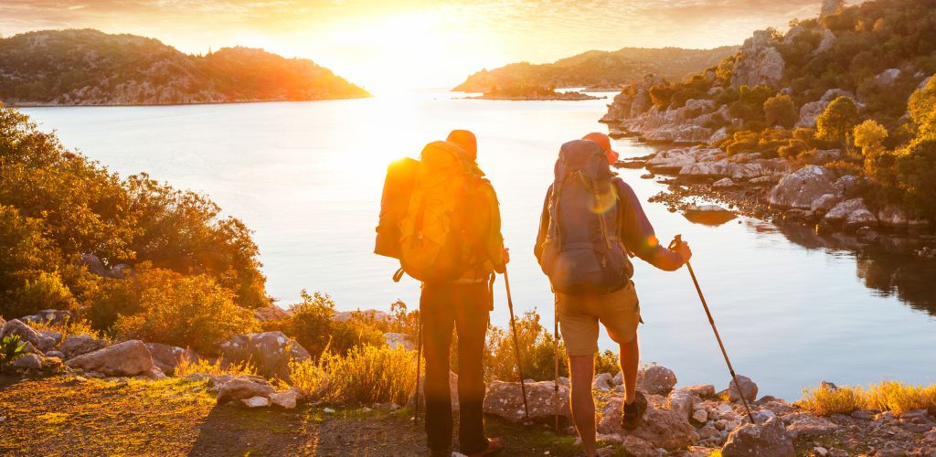 A two hikers beautiful landscape with mountain viewing a seawater at sunset. 