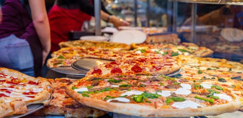 A table with full of different kinds of pizza. 