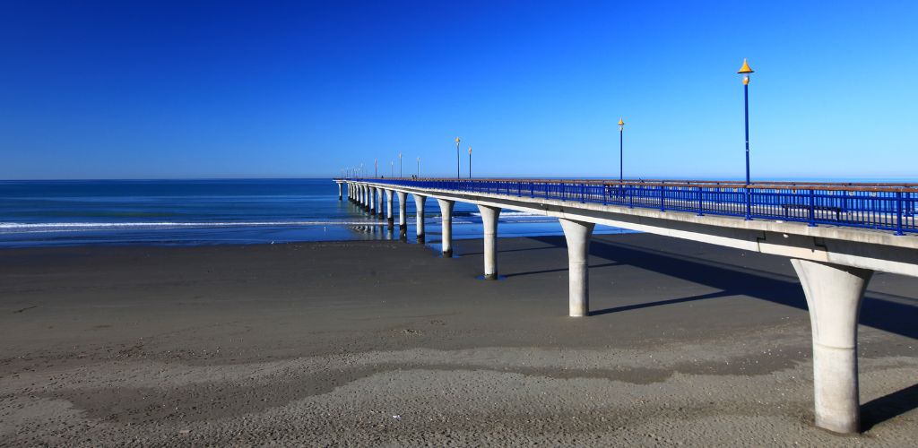A low tide beach with long bridge going into the sea.