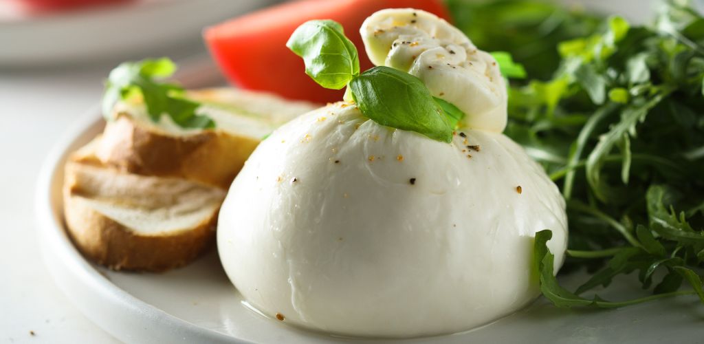 Fresh Burrata cheese with bread, arugula, and tomatoes.