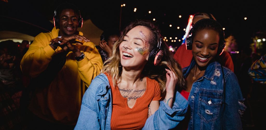 A young woman and man dancing at Silent Disco wearing a head set.