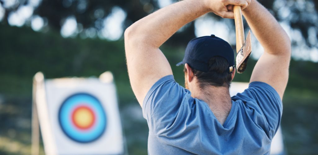 Man Axe Throwing at a Sports Range, Archery Training, or Practice with a Workbench Circle for Action, Game, and Fitness. Strong Person with Weapon for Tomahawk Competition, Gaming, and Park or Field with Target