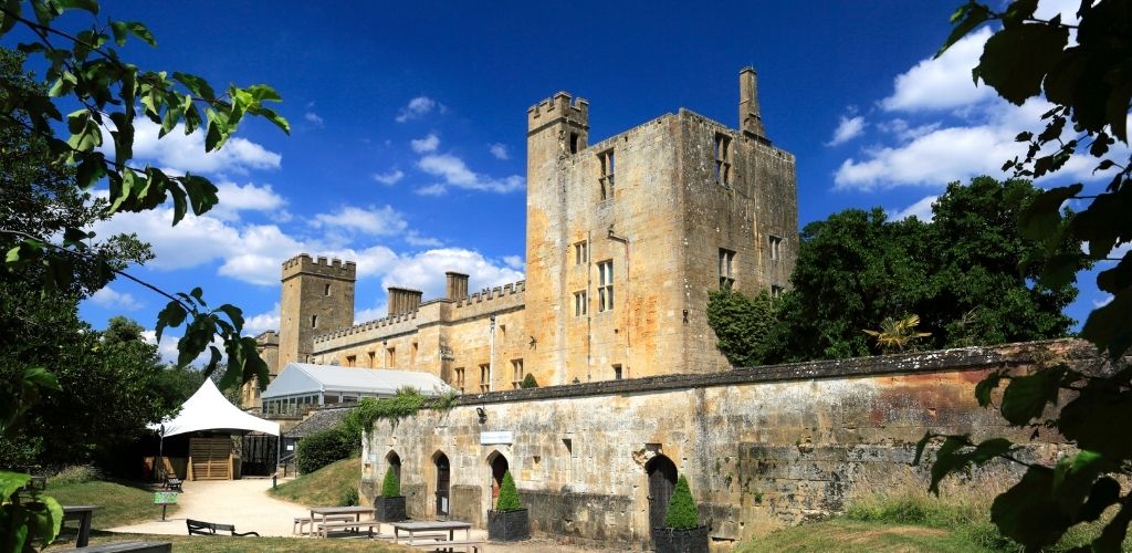 An old historical castle with a bench on the side and a white tent on the front. 