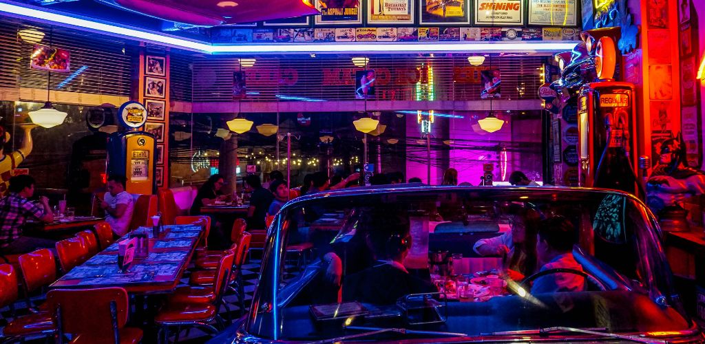 A dark American diner with people seated at tables.