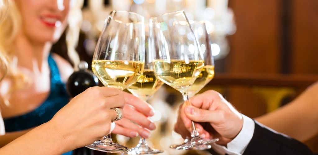 A group of people enjoying a toasting a glass of white wine.