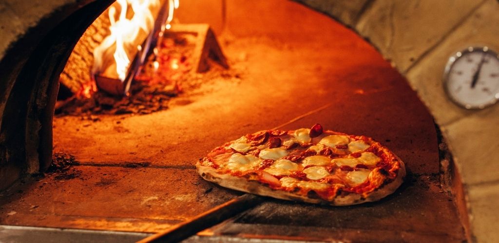 Italian pizza is cooked in a wood-fired oven.