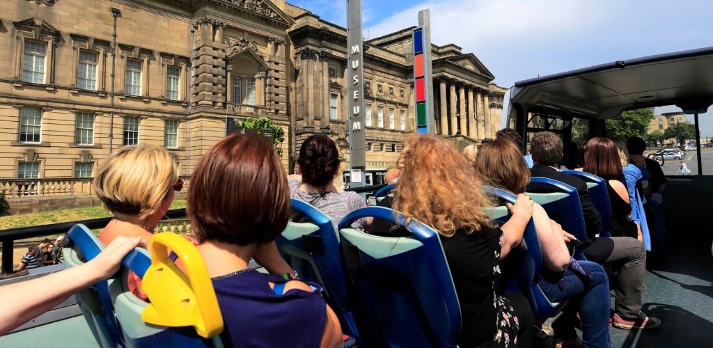 Tourists on the Hop on Hop off Bus and a Museum in the background. 