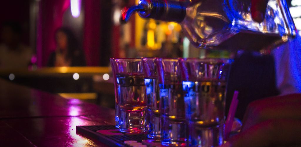 On the bar counter, a bartender filled a four-shot glass. 
