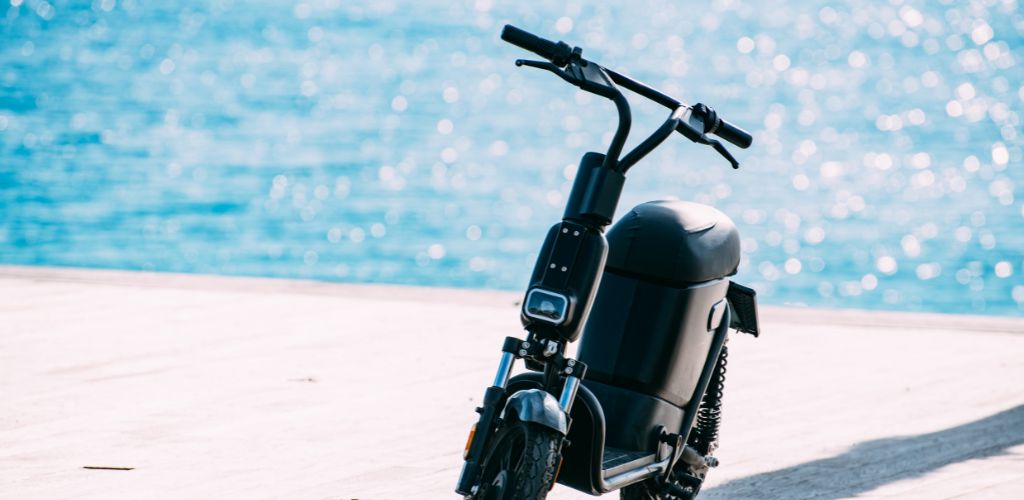 Beach in the background and an electric bike parked. 
