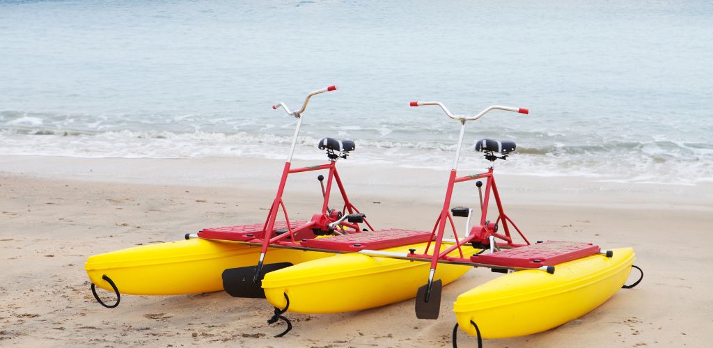 Two yellow water bikes at the show and a beach in the background. 