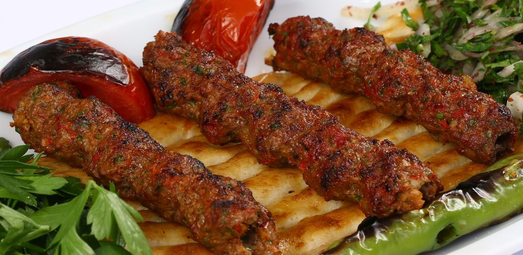 three barbecue beef, grilled tomato, grilled green pepper, green vegetables, and pita bread. 