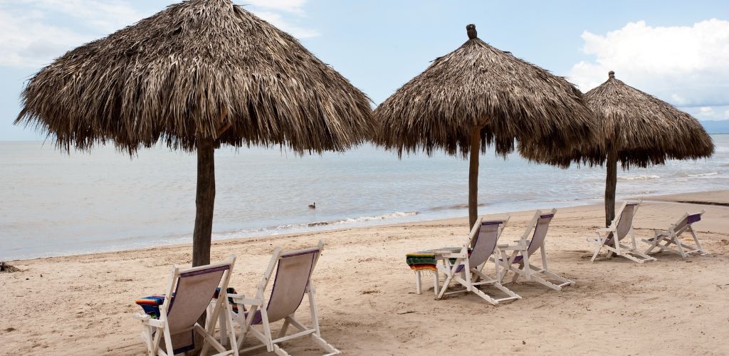 An umbrella and beach chair at the shore. white sand and clean water. 