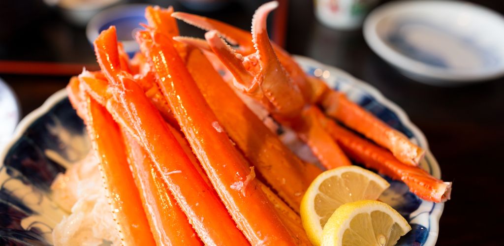 A plate of Fresh Crab Legs and a lemon. 