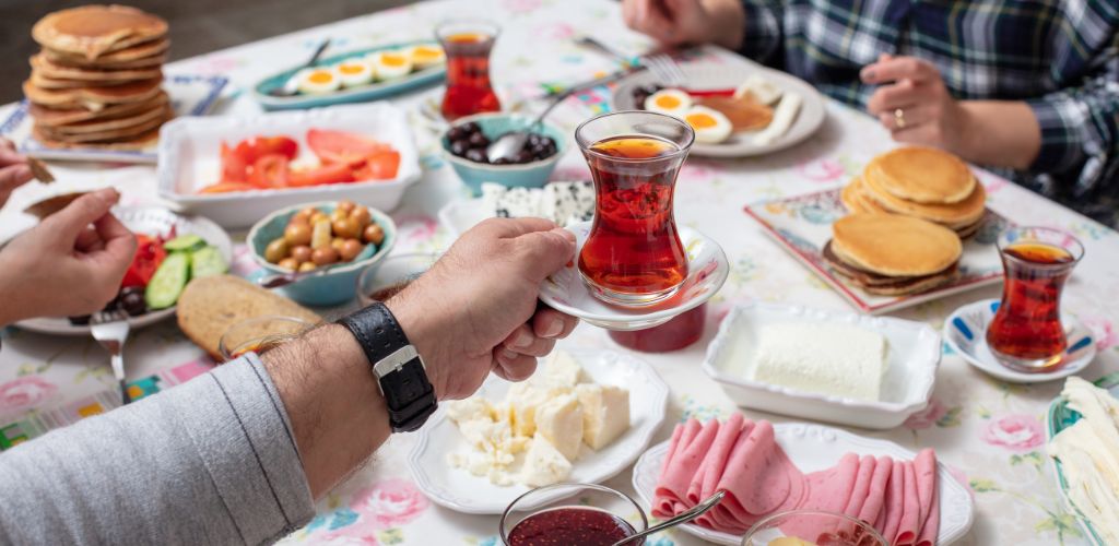 Turkish breakfast with simit, pancake, cheese, cherry tomato, cucumber, and tea on a table close-up view, selective focus. 