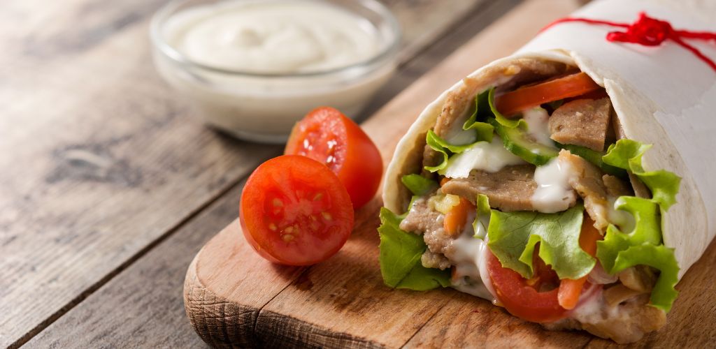 Doner kebab or shawarma sandwich on a wooden table. 