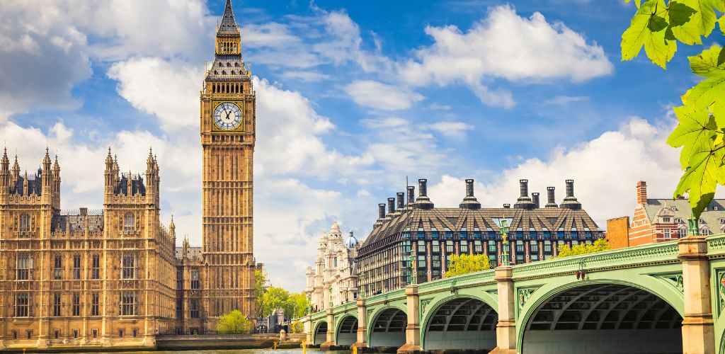 A historic building with a big clock tower. A view of a bridge and other building structures. 