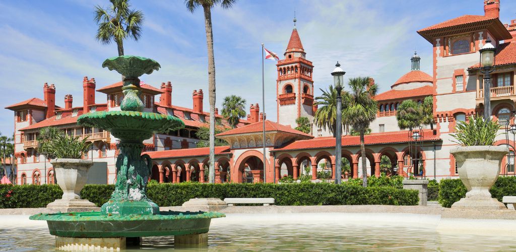 It is an old structure with plants and a fountain in front. 