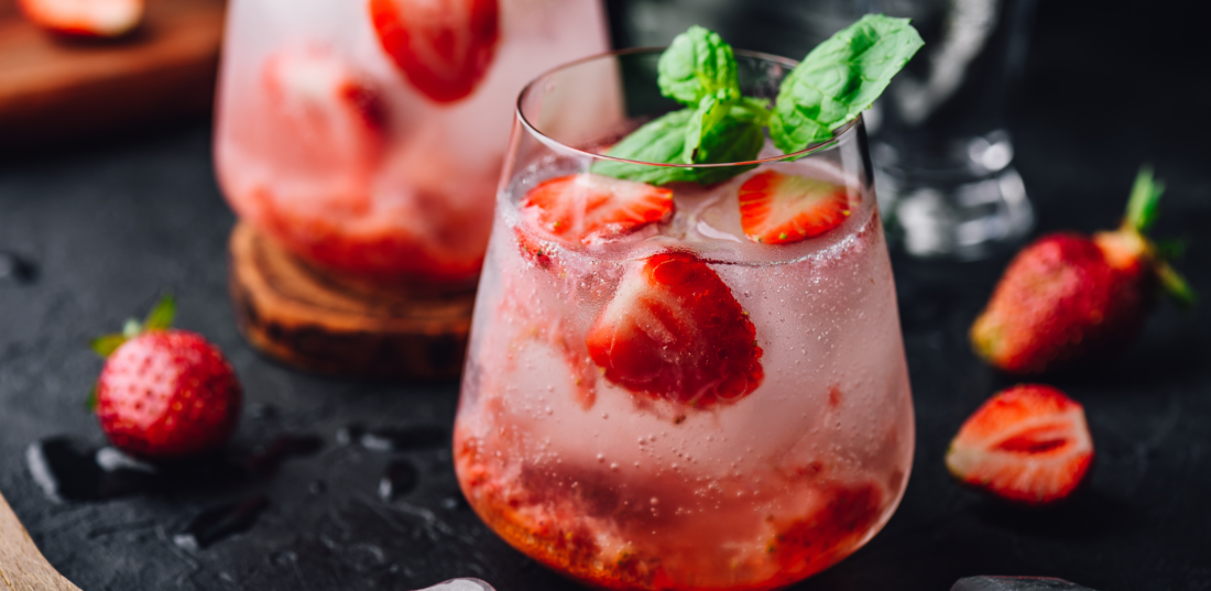 Two glasses of cocktail with fresh and frozen strawberry, gin and tonic. 