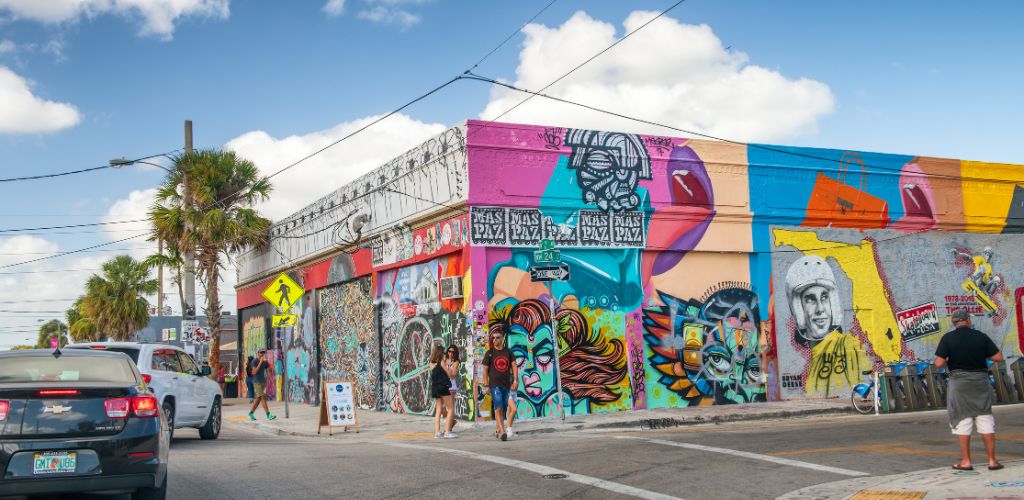 A sidewalk street with paint on the building's walls. 

