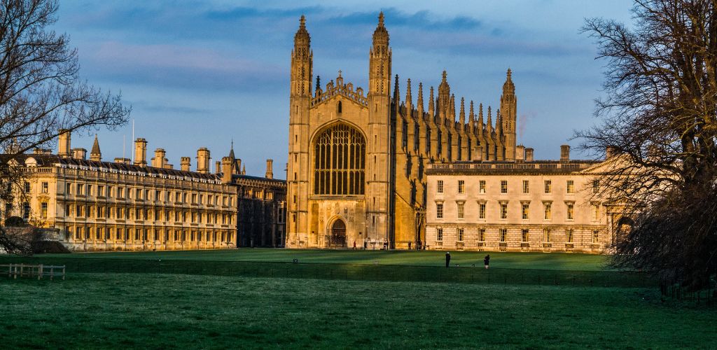 A historic university in London surrounded by green grass and trees. 