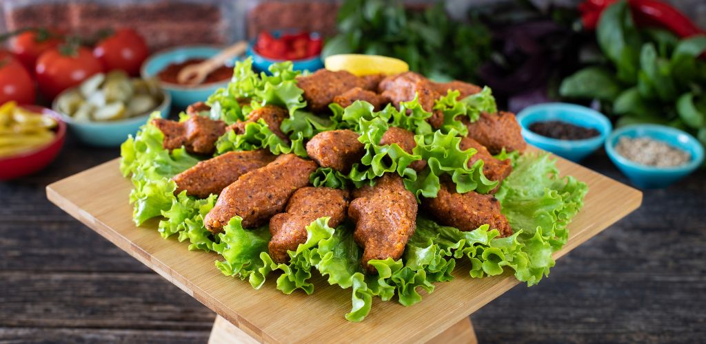 A raw meatball in Turkish with lettuce, tomato, pickle, and lemon, hot çiğköfte