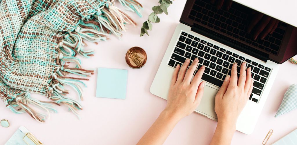 Flat lay home office desk. Female workspace with laptop, eucalyptus branch, accessories on pink background. Top view feminine background. Lifestyle blog. 