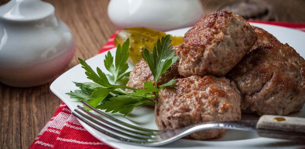 A meatballs and green leaf garnished and a fork on the side. 