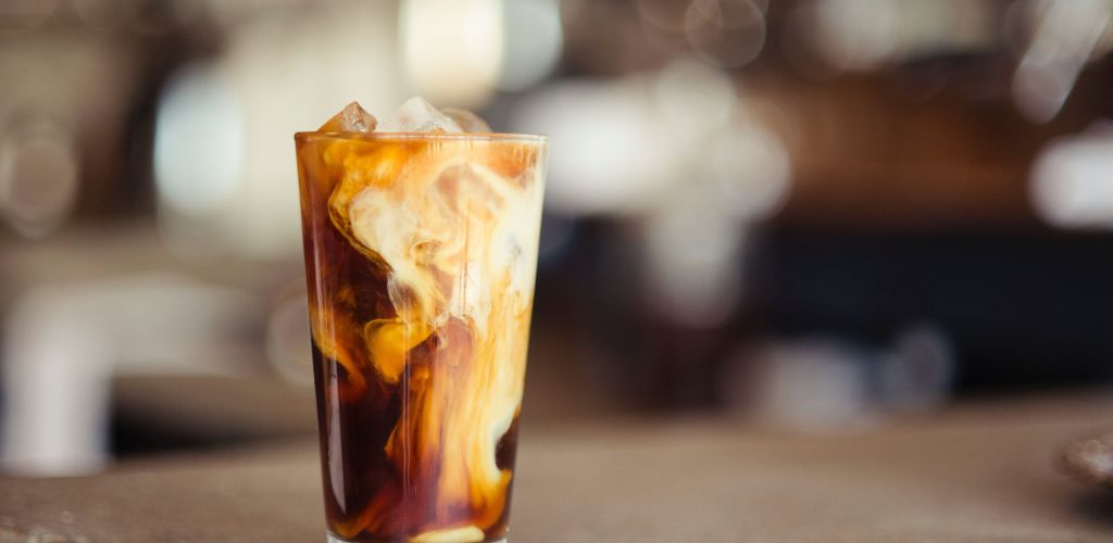 iced coffee with milk in a tall glass tumbler 