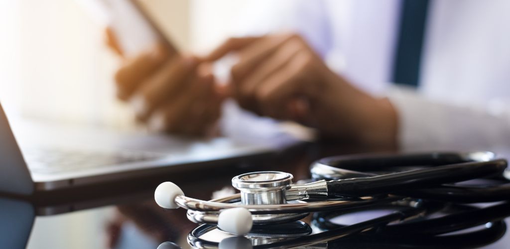 stethoscope and laptop with medical professional in background