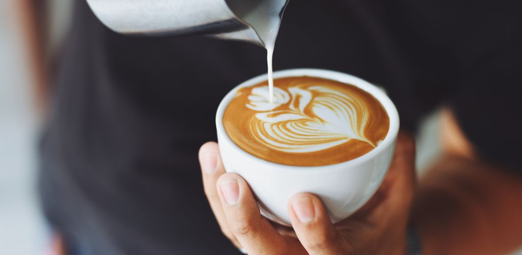 Barista pouring a flat white coffee